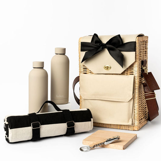 Adventure Awaits Gift Hamper with 2 beige Hydrer insulated water bottles, water resistant Aquanord picnic rug, beech wooden serving board and bottle opener. Housed in the Portable Wicker Picnic Basket. 