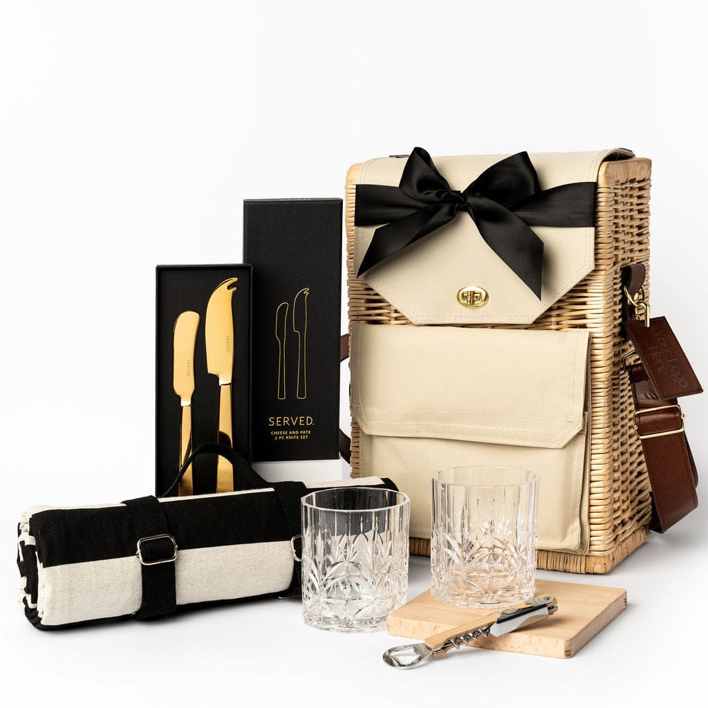 Picnic Essentials Ellar Boutique Gift Hamper with a Served Cheese and Pate Knife Set in Gold, a water resistant Aquanord Picnic Rug, Acryclic Etched Tumbler Set, Beech wooden serving board and bottle opener. Housed in the Portable Wicker Basket. 