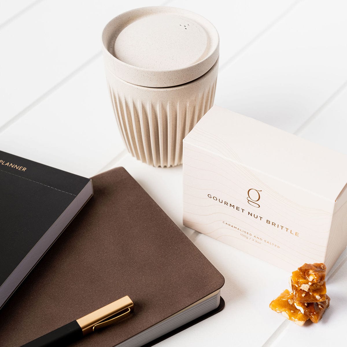 Corporate Gift details with a daily planner, notebook, gourmet nut brittle and a Huskee coffee cup. 