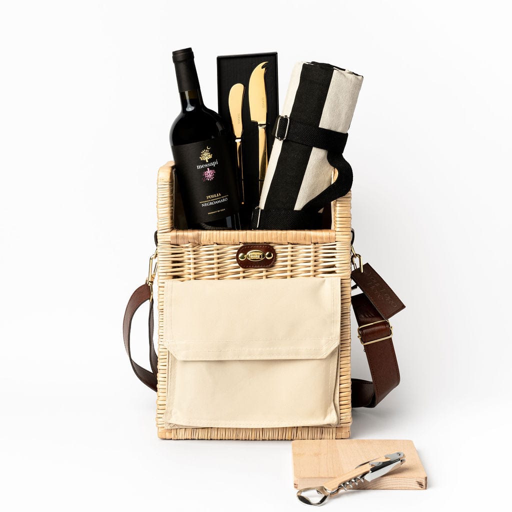 portable wicker basket with Messapi Italian wine, striped picnic rug, gold cheese knife set and a beech wooden board and bottle opener.