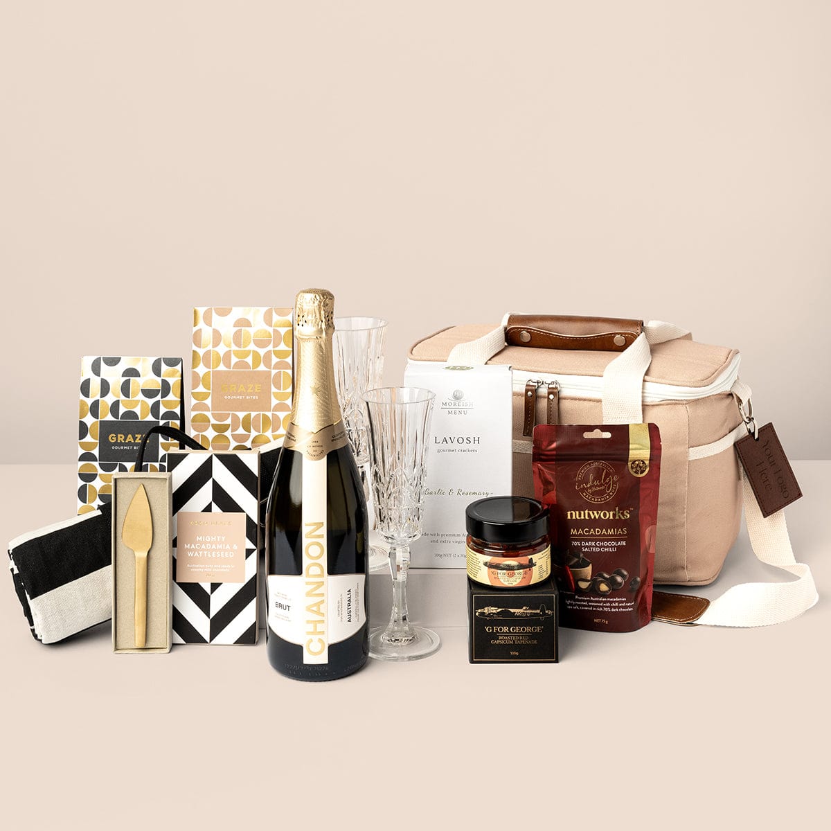 Taupe cooler bag gift with Chandon, a striped picnic rug, brass gold cheese knife, acrylic etched champagne flutes, graze gourmet bites, koko black chocolate bar, capsicum tapenade, nutworks macadamias and lavosh crackers.  
